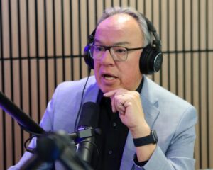 Nelson W. Bird, and Indigenous man with glasses, speaks into a microphone.